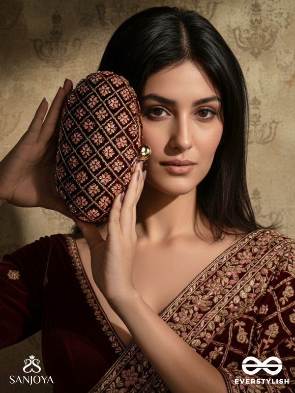 NAZRANA – CURVED MAROON SHADE TEXTILE CLUTCH WITH ORNAMENTED GRID EMBELLISHMENT AND GOLDEN METAL FRAME