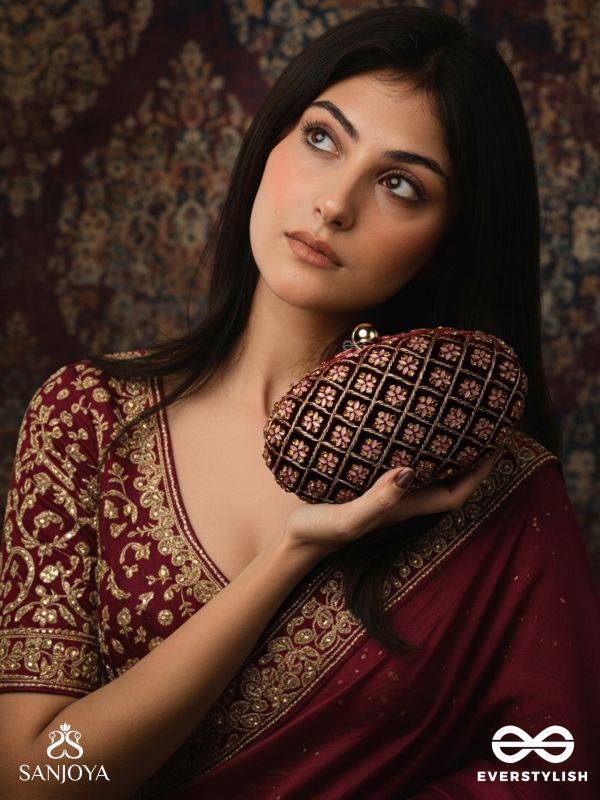 NAZRANA – CURVED MAROON SHADE TEXTILE CLUTCH WITH ORNAMENTED GRID EMBELLISHMENT AND GOLDEN METAL FRAME