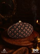 NAZRANA – CURVED MAROON SHADE TEXTILE CLUTCH WITH ORNAMENTED GRID EMBELLISHMENT AND GOLDEN METAL FRAME