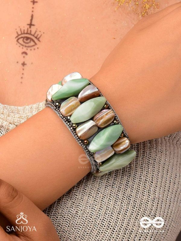 Shuktimālā- Shell band-Expandable bracelet crafted from shell beads, combining turquoise and beige-brown tones with a brassy finish.