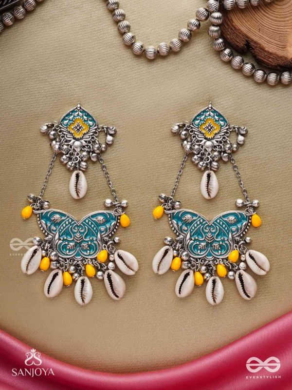 SHANKHA PUSHPA- CONCH BLOSSOM-OXIDIZED EARRINGS WITH PASTEL-HUED METALWORK, EMBELLISHED WITH DELICATE COWRIE SHELLS, YELLOW BEADS AND GHUNGROO